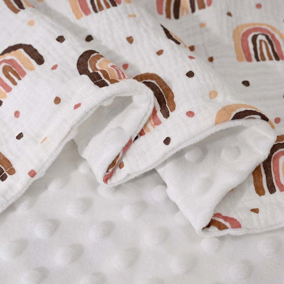 Close-up view of a rainbow-patterned blanket showing the soft texture of the minky fabric, highlighting its intricate stitching.