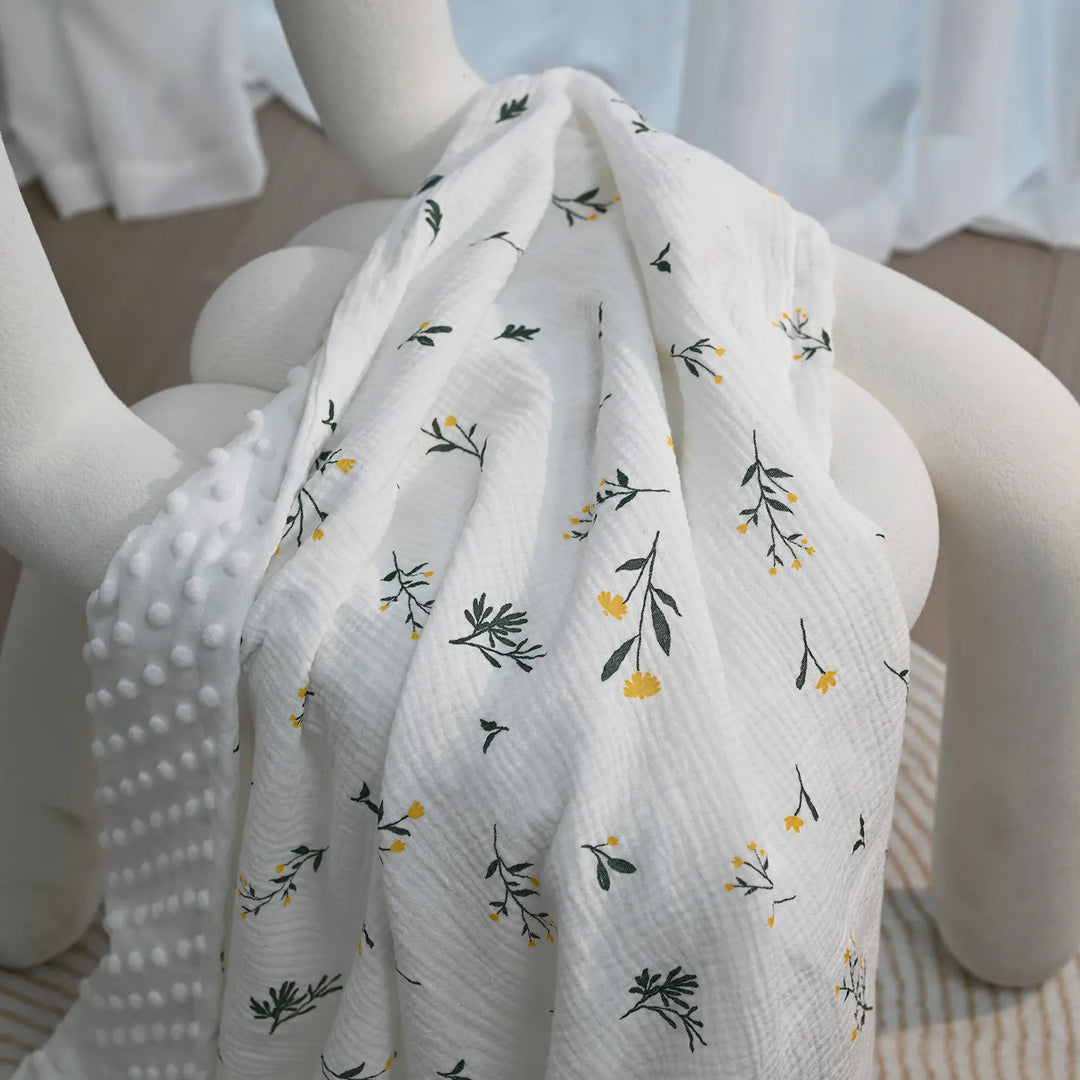 A floral-patterned baby blanket with minky backing draped elegantly over a chair, highlighting its delicate design and texture.