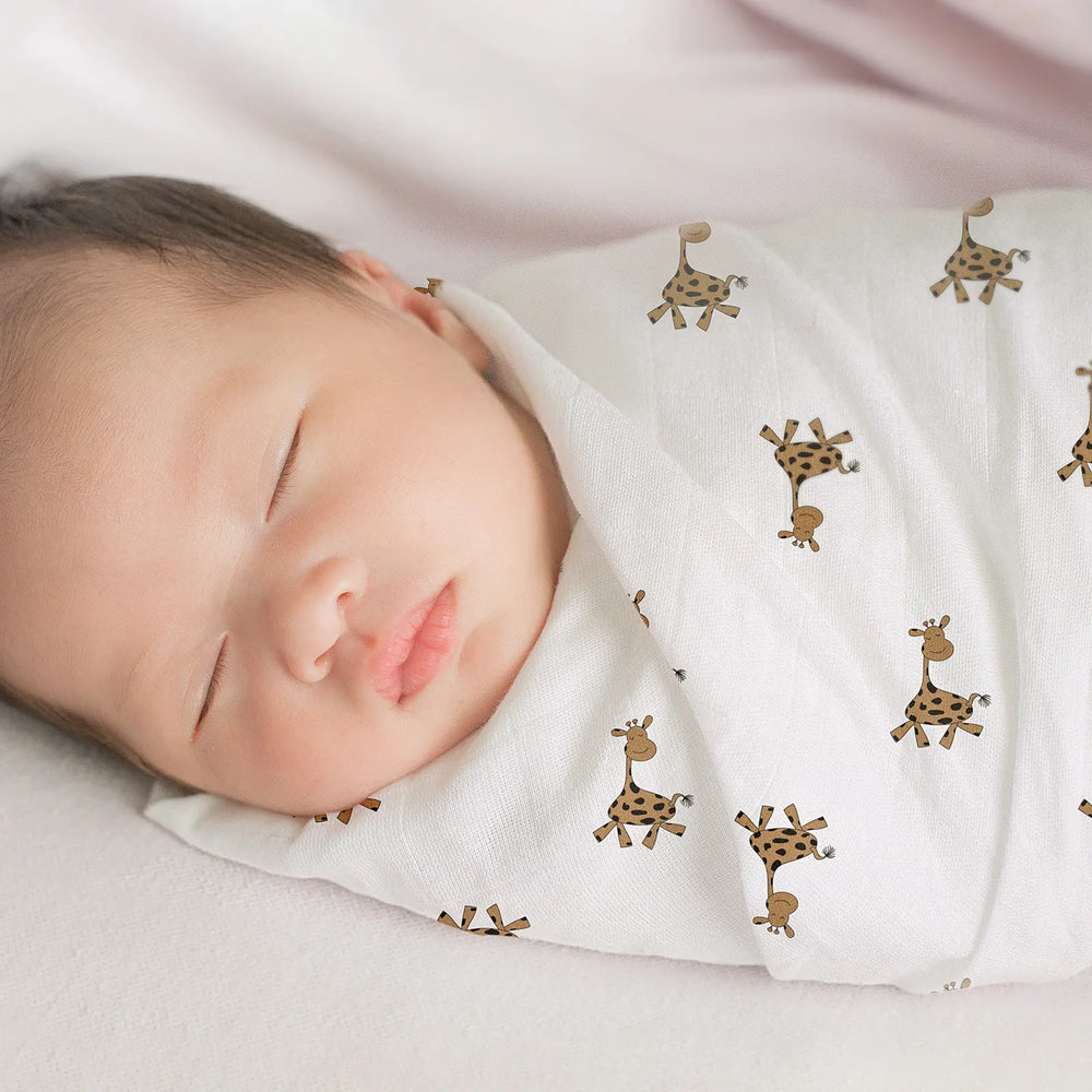 Newborn baby sleeping soundly wrapped in a soft muslin swaddle blanket with a cute giraffe print. Gentle, breathable fabric ideal for infant comfort.