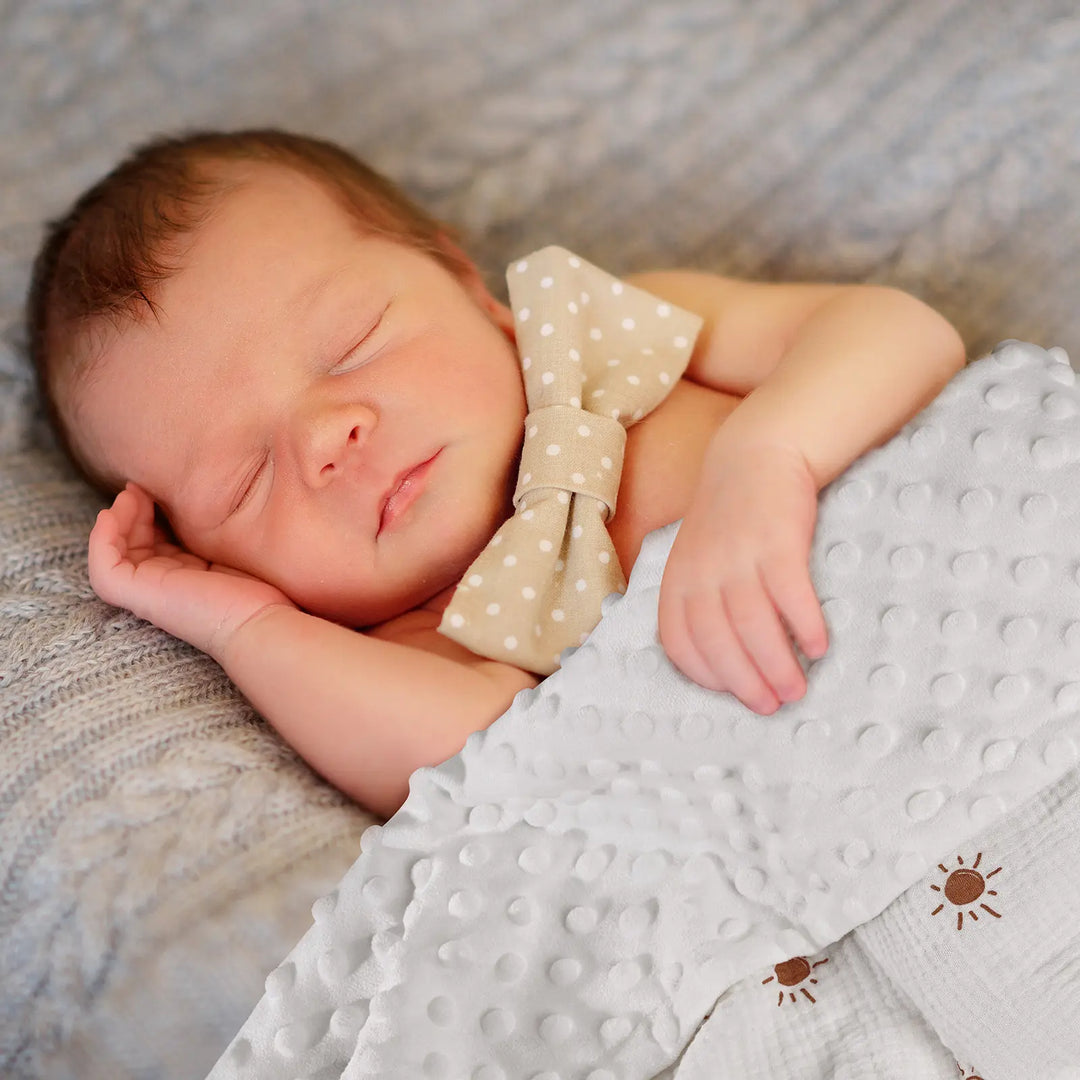 Newborn baby sleeping peacefully wrapped in an ultra-soft Minky blanket with sun print design - hypoallergenic and perfect for babies’ delicate skin.