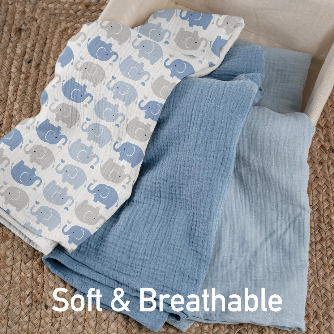 Soft and breathable muslin swaddle blankets in blue tones with elephant pattern, displayed on natural jute rug showing texture detail